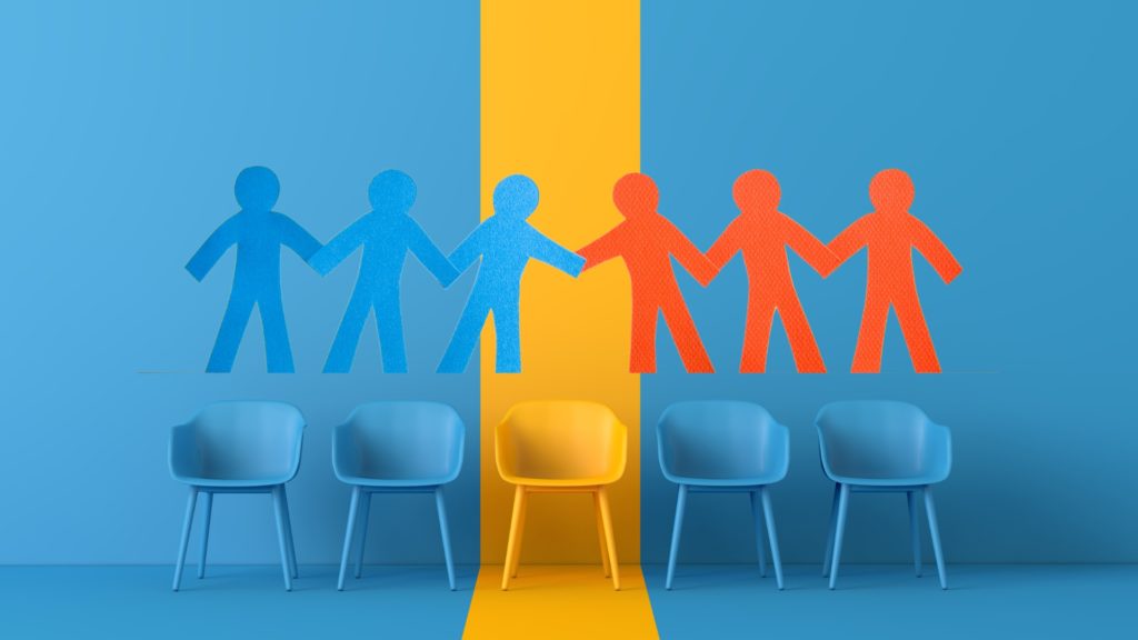 Illustration of blue and orange human cutouts holding hands above a row of chairs, symbolising workplace diversity and collaboration.